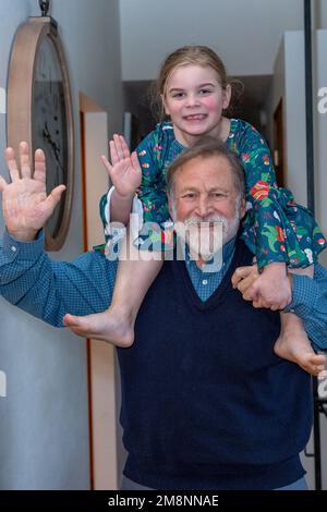 Grand-père qui s'amuse à offrir à sa petite-fille de six ans une promenade en pigeyback dans un couloir. (M.) Banque D'Images