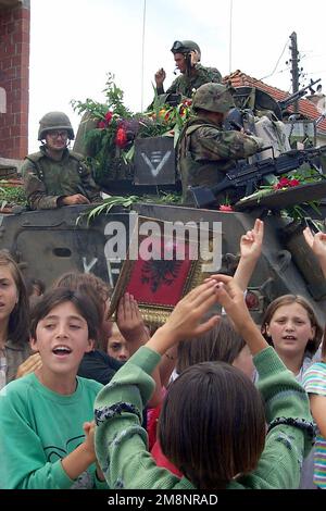 ÉTATS-UNIS Les Marines de l'unité expéditionnaire maritime (UMM) de 26th, 3rd Bataillon, 8th Marines, au sommet d'un porte-personnel blindé, reçoivent un accueil chaleureux avec des roses et des chants par les enfants d'une ville locale près de la base opérationnelle avant au Kosovo. Des éléments du MEU de 26th ont été déployés à partir de navires du Groupe de préparation amphibie 2 (non illustré) à l'appui de l'opération menée par l'OTAN. Objet opération/série: ETAT TUTEUR COMMUN: Kosovo pays: Yougoslavie (YUG) Banque D'Images