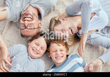 Les parents épris sans souci d'en haut chatouiller et taquiner leurs petits enfants riant mignon. Bonne famille de quatre personnes de race blanche se détendant et jouant ensemble Banque D'Images