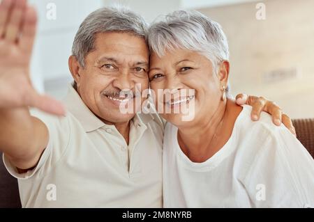 Portrait d'un couple senior de race mixte souriant qui prend le selfie à la maison. Un mari et une femme hispaniques heureux prenant des photos pour les médias sociaux à la maison. Personnes âgées Banque D'Images