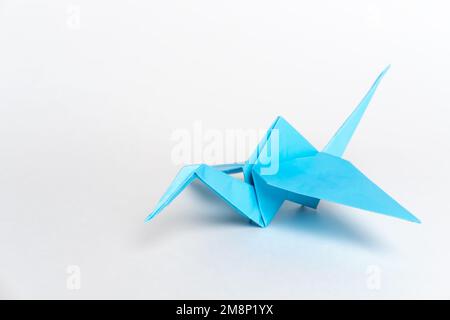 Grues traditionnelles japonaises d'origami en papier bleu sur fond blanc. La créativité des enfants. Un symbole de paix. Banque D'Images