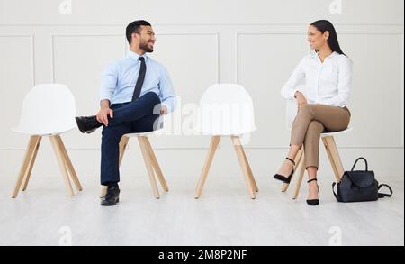 Deux hommes d'affaires parlent en attendant une entrevue. Homme d'affaires asiatique souriant et femme d'affaires mixte de race gardant les distances sociales. Candidat dans Banque D'Images