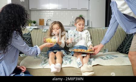 Les enfants aiment s'asseoir parmi l'argent et recevoir la nourriture des parents Banque D'Images