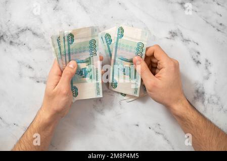 Homme comptant de l'argent, la monnaie du rouble russe sur un fond clair. Le concept de la finance et de la rentabilité du travail Banque D'Images