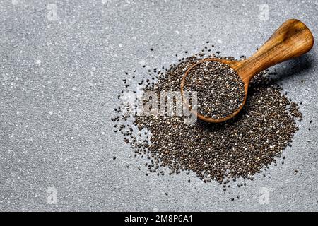 vue de dessus des graines de chia dans une pelle en bois sur fond gris Banque D'Images