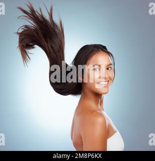 Portrait d'une femme hispanique brunette avec de longs cheveux luxuriants et beaux souriant et posant sur un fond gris studio. Race mixte femelle debout Banque D'Images