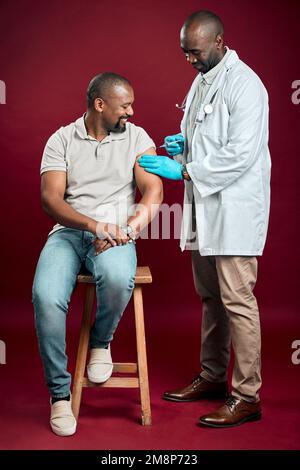 Un médecin afro-américain donne le vaccin contre le covid à un homme noir portant un masque chirurgical. Patient en pleine longueur et en bonne santé qui reçoit une injection de corona Banque D'Images