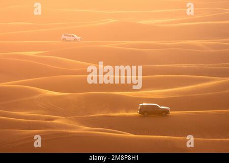Deux 4x4 offroad se disputant sur la crête des dunes dans un paysage sablonneux pendant l'heure d'or Banque D'Images