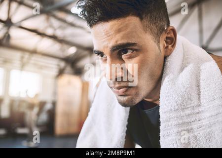 Jeune homme portant une serviette après un entraînement. Faites une pause à l'athlète. La salle de gym est l'endroit où il vient se détendre. Repose-bodybuilder concentré Banque D'Images