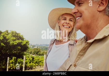 Couple senior souriant se liant pendant la journée sur une ferme avec copyspace. Heureux mari et femme caucasiens debout ensemble sur le vignoble en été Banque D'Images