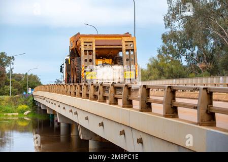 Un camion semi-remorque transporte un gros camion de transport minier à travers le pont Peter Sinclair à Nyngan vers Cobar, dans le nord-ouest de la Nouvelle-Galles du Sud, en Australie Banque D'Images