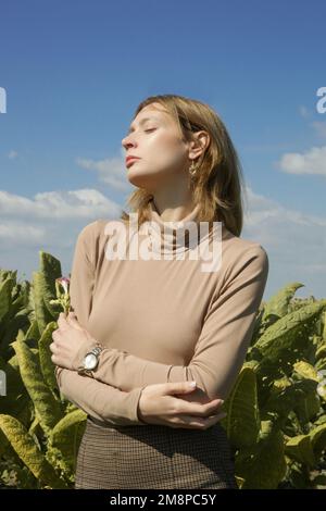 Portrait d'extérieur de la mannequin en coton beige à col roulé et pantalon skinny marron. Photoshoot de mode sur une journée ensoleillée dans la nature. Banque D'Images