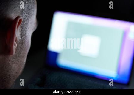Concept de piratage. Hacker mâle regardant l'écran d'ordinateur dans la pièce sombre Banque D'Images