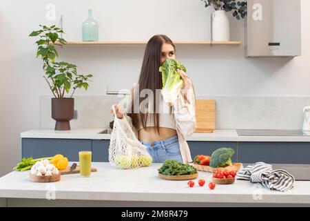 Une brunette attrayante tire les légumes frais d'un sac réutilisable. Végétarisme. Banque D'Images