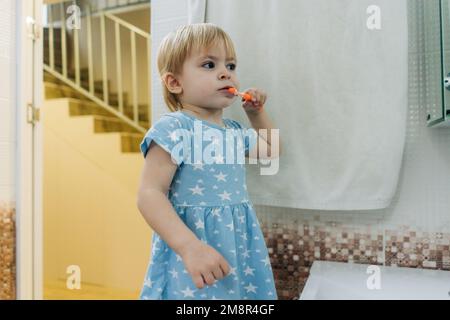 Une petite fille se brosse les dents dans la salle de bains. Banque D'Images