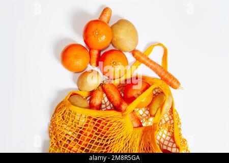 Sac en maille orange. Vue de dessus. Fruits et légumes frais du marché agricole. Pommes de terre crues, carottes crues, pommes, mandarines, oranges. Consci Banque D'Images