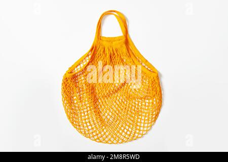 sac à provisions en filet. Sac réutilisable. Végétarisme, régime alimentaire brut, consommation consciente, grille. sac en maille orange sur fond blanc. Vue de dessus Banque D'Images