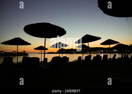 Plage sur la mer Méditerranée dans la Reviera turque. Côte au coucher du soleil avec parasols près d'Alanya en Turquie. Banque D'Images