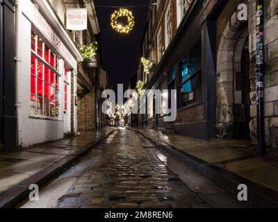 Les ruines, rue médiévale historique à York à l'heure de Noël avec rue pavée humide Banque D'Images