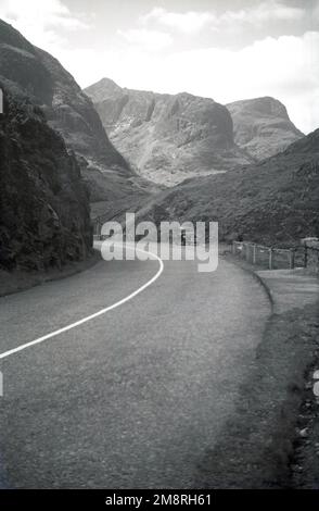 1951, historique, Scottish Highlands, vue de la A82 de la chaîne de montagnes de Glencoe dans les montagnes de l'Écosse, Royaume-Uni. Voiture de l'époque garée en layby sur le côté de la route sinueuse. Banque D'Images