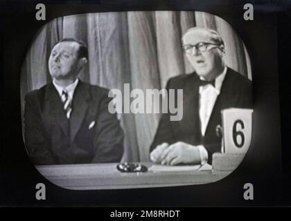 1957, historique, deux panélistes masculins sur une émission de télévision de la BBC, à droite, l'écrivain et le grand-acteur Alan Melville. L'un des premiers personnages de la télévision britannique, Melville était un homme de talent multiple, ayant écrit (et lu) des histoires pour l'heure des enfants de la BBC alors qu'il n'avait que 22 ans. Il allait écrire des scripts, des revues, des pièces de théâtre et des comédies musicales et comme un broacaster apparaissent régulièrement à la télévision dans des programmes populaires, tels que The Brain's Trust et What's My Line?, ainsi que sa propre série, comme le Sketch show, avant le Fringe. Banque D'Images