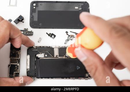 Technicien répare l'intérieur de la carte mère du smartphone avec des outils de récupération Banque D'Images
