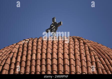 Dôme en argile traditionnel de l'église orthodoxe grecque avec une croix métallique contre un ciel bleu. Banque D'Images
