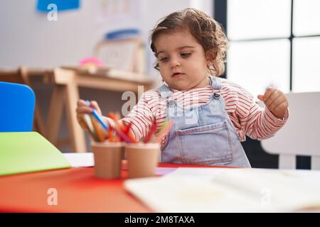 Adorable étudiante hispanique de fille assise sur table de dessin sur papier à la maternelle Banque D'Images