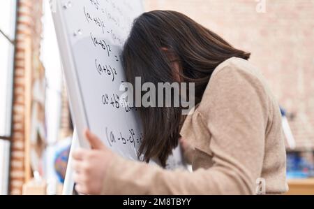 Adorable fille hispanique étudiant en mathématiques de résolution exercice stressé avec la tête sur le tableau de surveillance en classe Banque D'Images