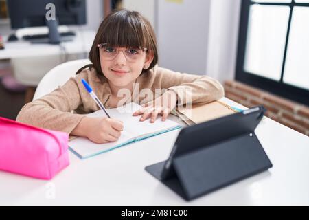 Adorable jeune fille hispanique étudiante assise sur une table étudiant en classe Banque D'Images