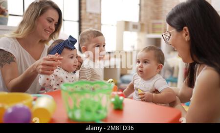 Les enseignants et les élèves d'âge préscolaire jouant avec des jouets sur la table de la maternelle Banque D'Images