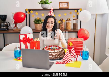 Femme hispanique célébrant l'anniversaire avec un grand gâteau au chocolat faisant appel vidéo faisant signe ok avec les doigts, souriant sympathique gestant excellent symbole Banque D'Images