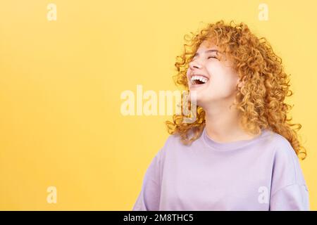 Femme avec des cheveux bouclés et des vêtements décontractés riant Banque D'Images