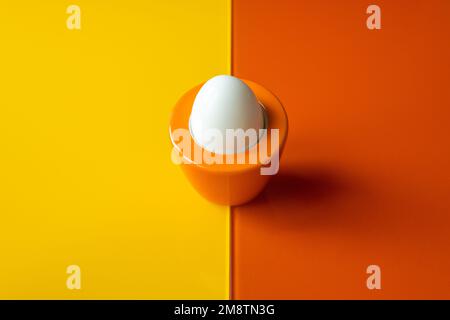 Œuf dur sur fond jaune-orange, design original, concept de revitalisation, nutriments précieux, protéines et vitamines Banque D'Images
