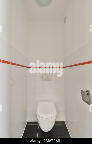 une toilette blanche dans une salle de bains avec des carreaux rouges et blancs sur le mur derrière elle est une cabine de douche ouverte Banque D'Images