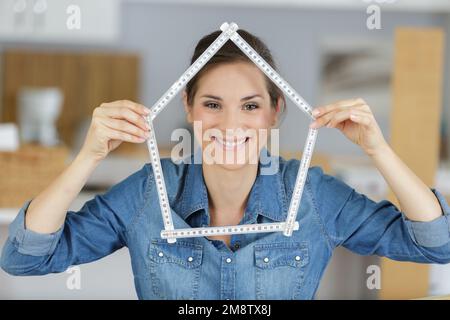 femme tenant une règle sous la forme d'une maison Banque D'Images