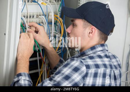 un technicien de maintenance vérifie les câbles dans un serveur Banque D'Images