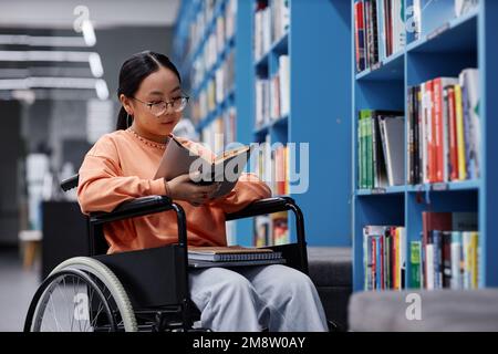 Portrait de la jeune femme asiatique avec un handicap livre de lecture à la bibliothèque, concept d'inclusion étudiante Banque D'Images