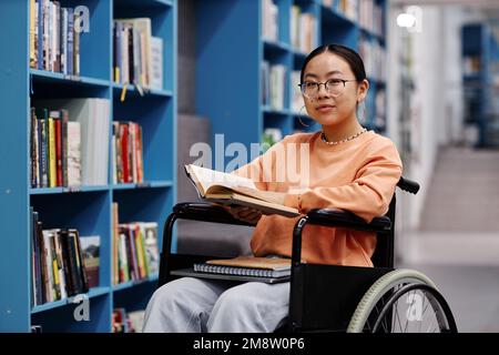 Portrait d'une jeune femme asiatique handicapée dans un cadre de bibliothèque à l'université moderne en souriant à la caméra Banque D'Images