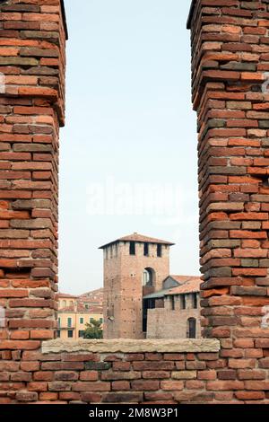 Une tour d'une ancienne forteresse médiévale à travers un trou d'embrasure dans un mur de briques brunes Banque D'Images