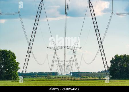 Rangée de pylônes de soutien de ligne d'alimentation sur le champ de campagne. Paysage industriel. Banque D'Images