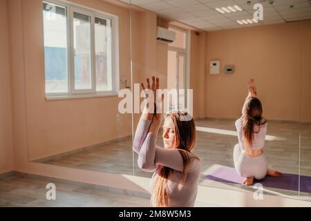 Vue de dessus. Une belle jeune femme en vêtements de sport rose est engagée dans le yoga, sport dans le hall sur un tapis violet. Yoga, sport et concept sain. Banque D'Images