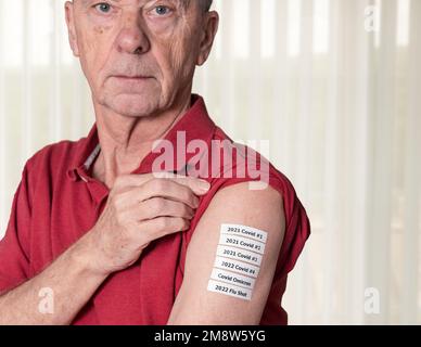 Homme adulte senior montrant tous les vaccins contre Covid et la grippe ou la vaccination dans son épaule pendant la pandémie Banque D'Images