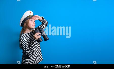 Bannière d'une fille de marin sur un fond bleu adolescente dans un costume de marin avec un binoculaire regardant dans la distance Banque D'Images