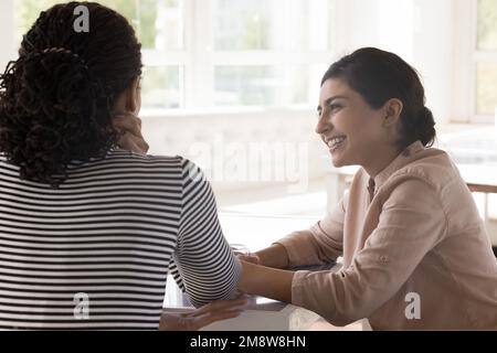 Bonne femme indienne et amie africaine assise à table Banque D'Images