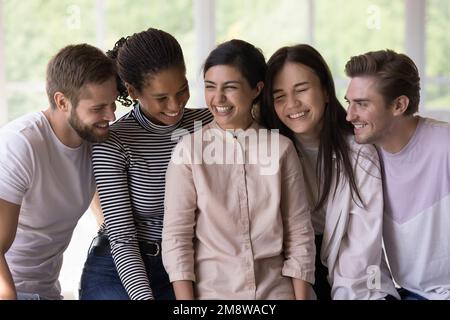 Des amis multiethniques joyeux et joyeux, assis à proximité, discutant Banque D'Images