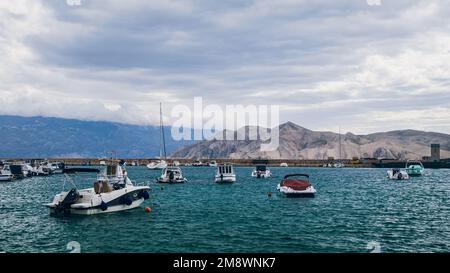 Une belle vue de petits bateaux ancrés dans la baie de la ville de Baska sur l'île de Krk en Croatie avec la montagne en arrière-plan Banque D'Images