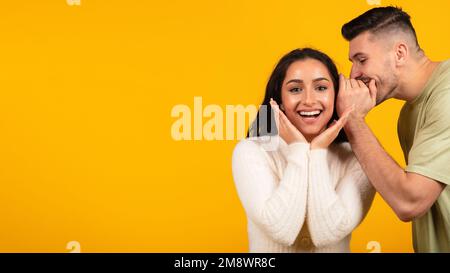Joyeux garçon arabe millénaire chuchotant le secret à la femme à l'oreille, excitée femme inspirée se réjouit et écoute des potins Banque D'Images