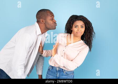 Reste loin de moi. Couple afro-américain, homme d'âge moyen amoureux atteignant et essayant d'embrasser une jeune femme confuse Banque D'Images