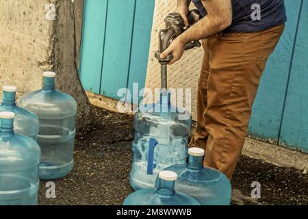 Jeune homme remplissant des bidons de cinq gallons pour une utilisation en cabine sèche - sans eau courante - en Alaska USA Banque D'Images